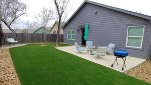 Ein Garten mit einer Terrasse, einem Grill und Gartenmöbeln.