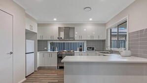 A modern kitchen with white cabinets, a built-in oven, a microwave, and a large island.