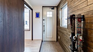 Passadís amb paret de fusta, una porta i esquís penjats a la paret.