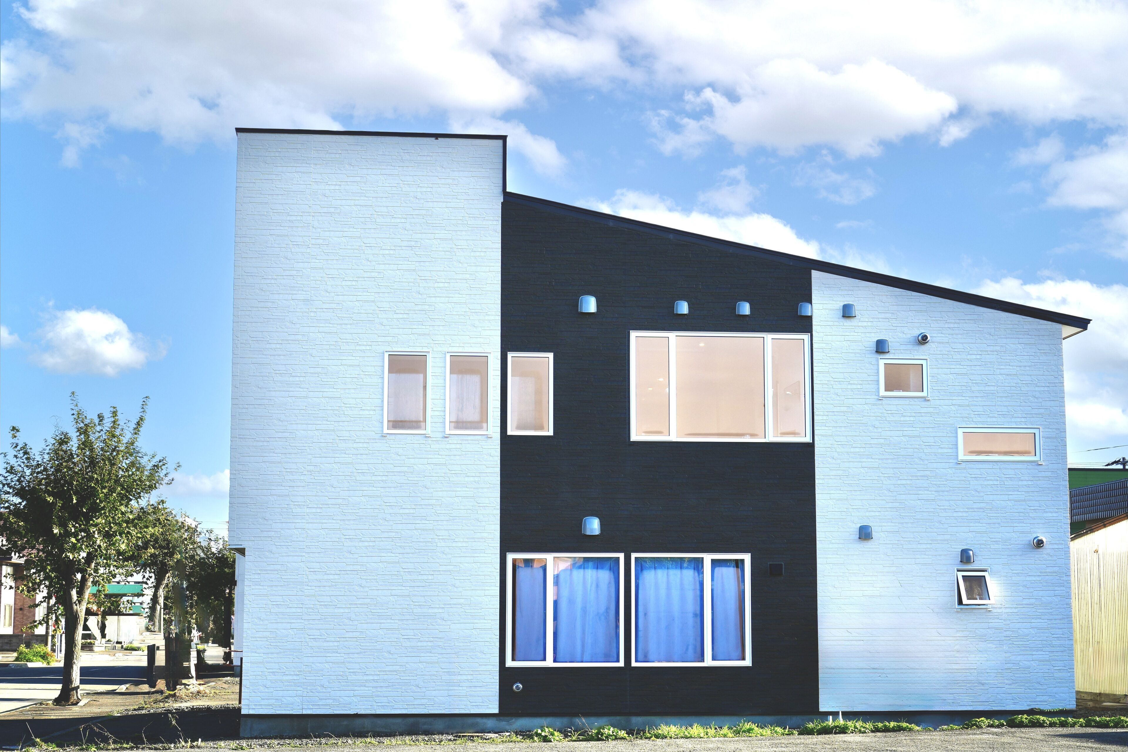 Un bâtiment moderne à deux étages, doté d’un toit plat, de grandes fenêtres et d’une porte de garage bien visible.