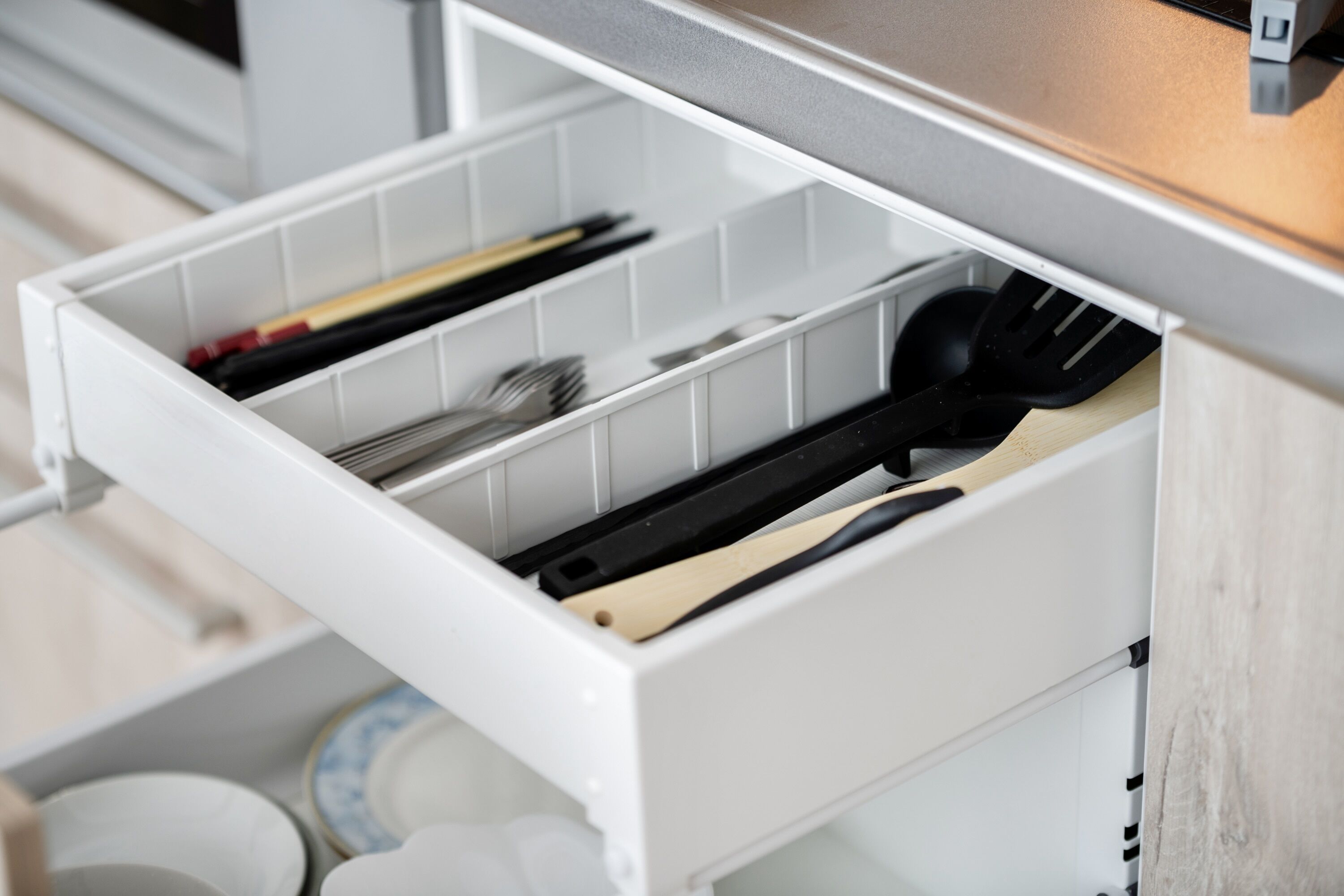 Un cajón de cocina con utensilios.