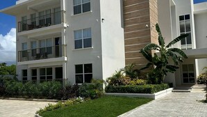 A modern multi-story hotel with a flat roof, large windows, and a landscaped garden area.