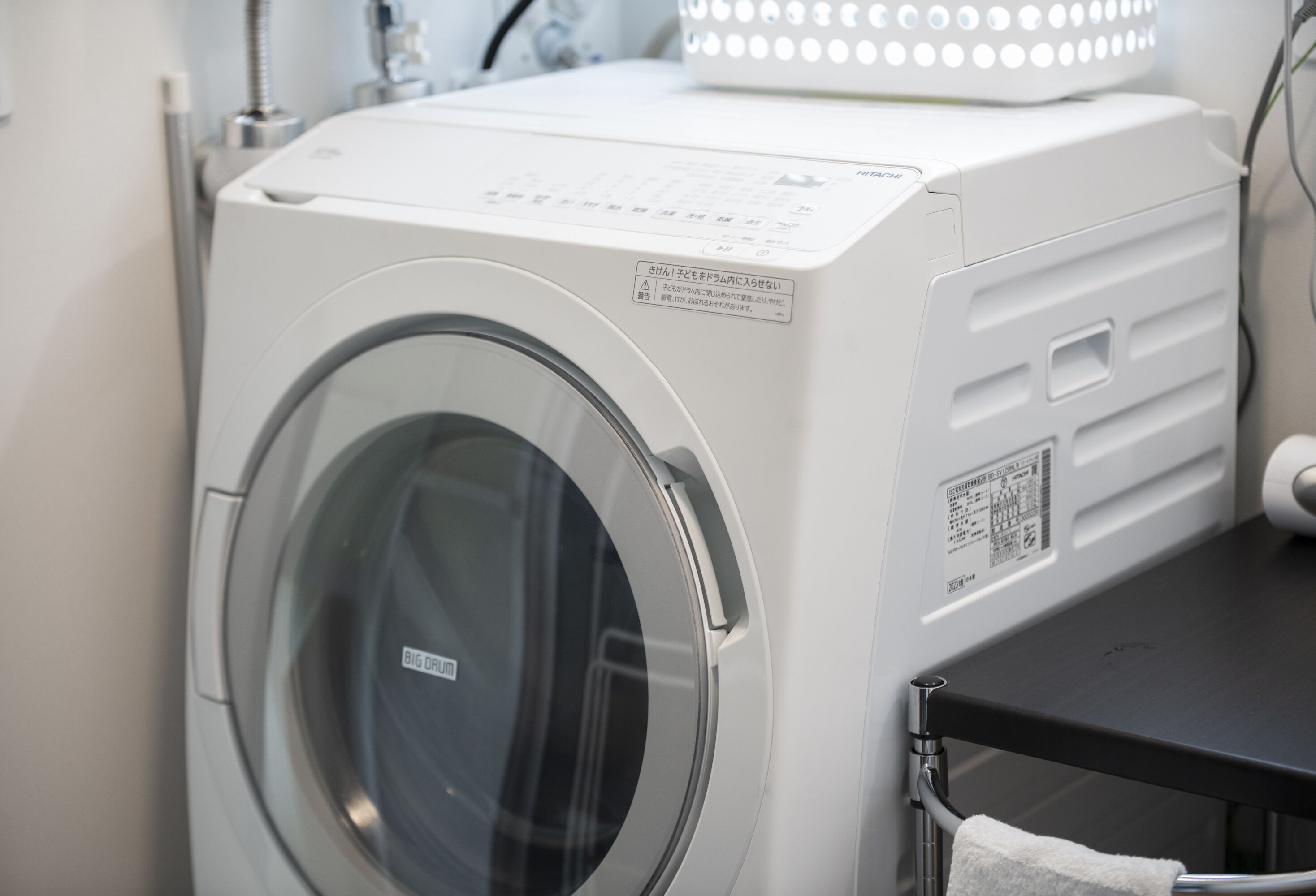 A front-loading washing machine with a control panel and a label in a foreign language.