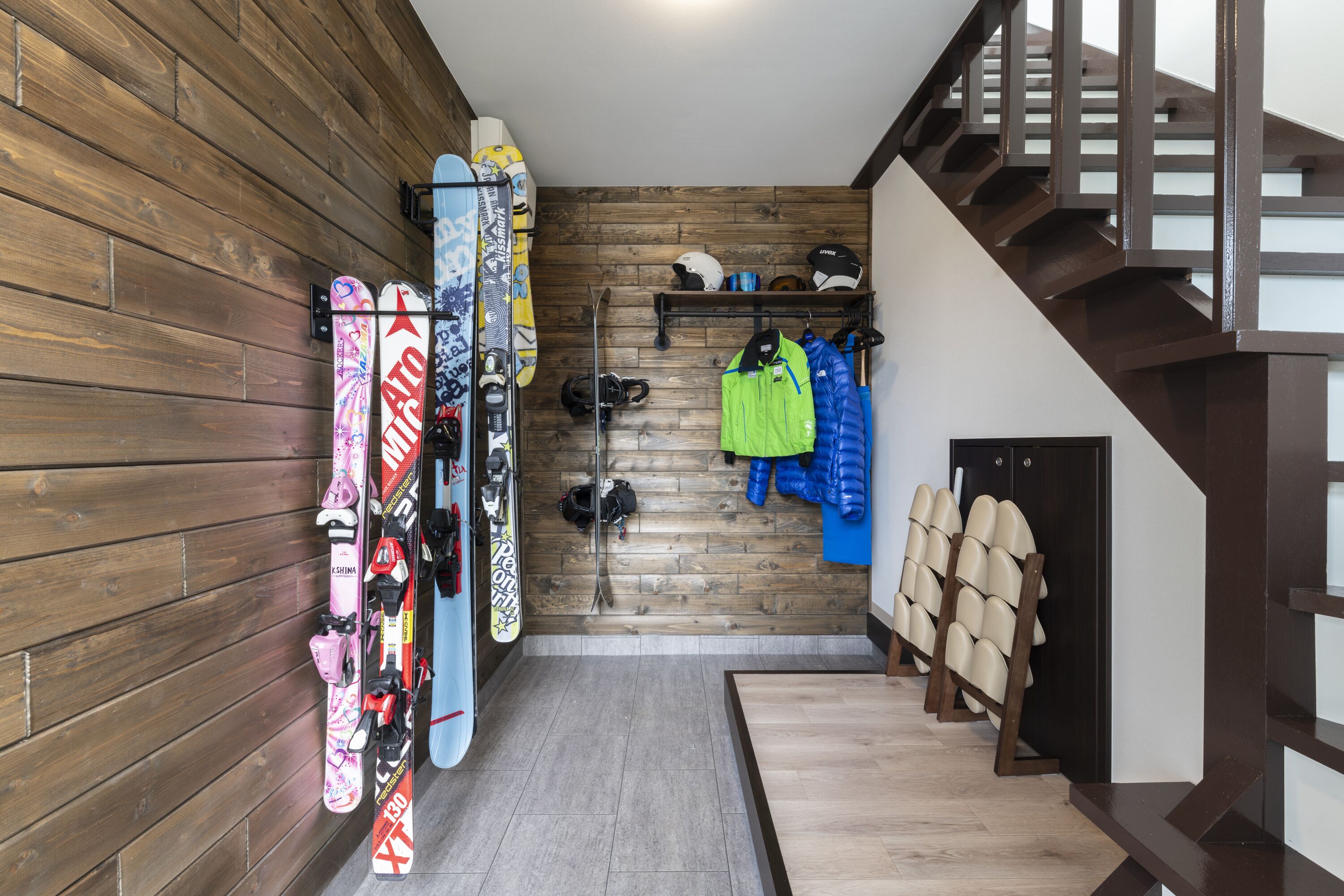 Interior de madera con una escalera, equipo de esquí y un perchero para abrigos.