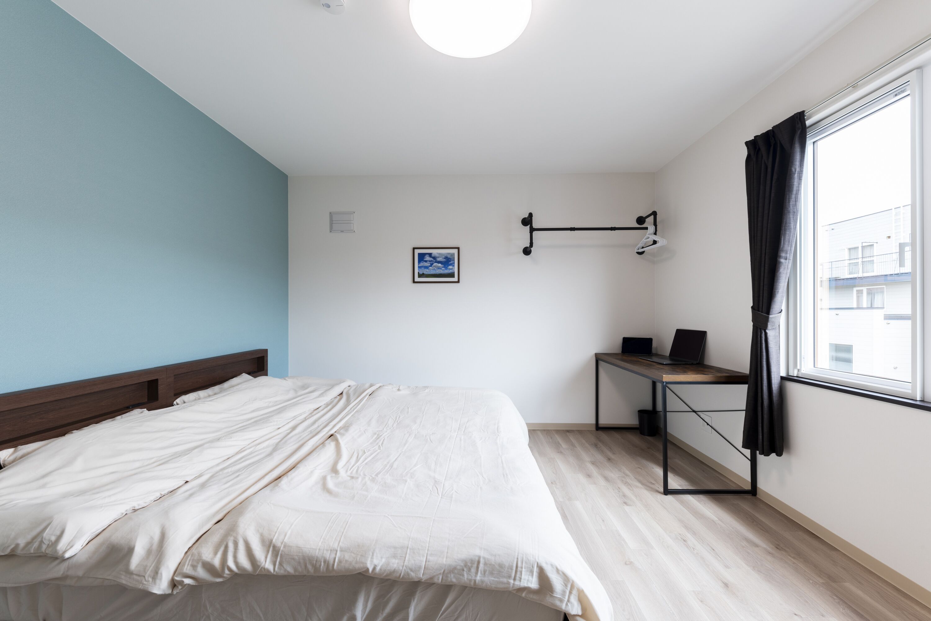 A bedroom with a bed, a desk, and a window.