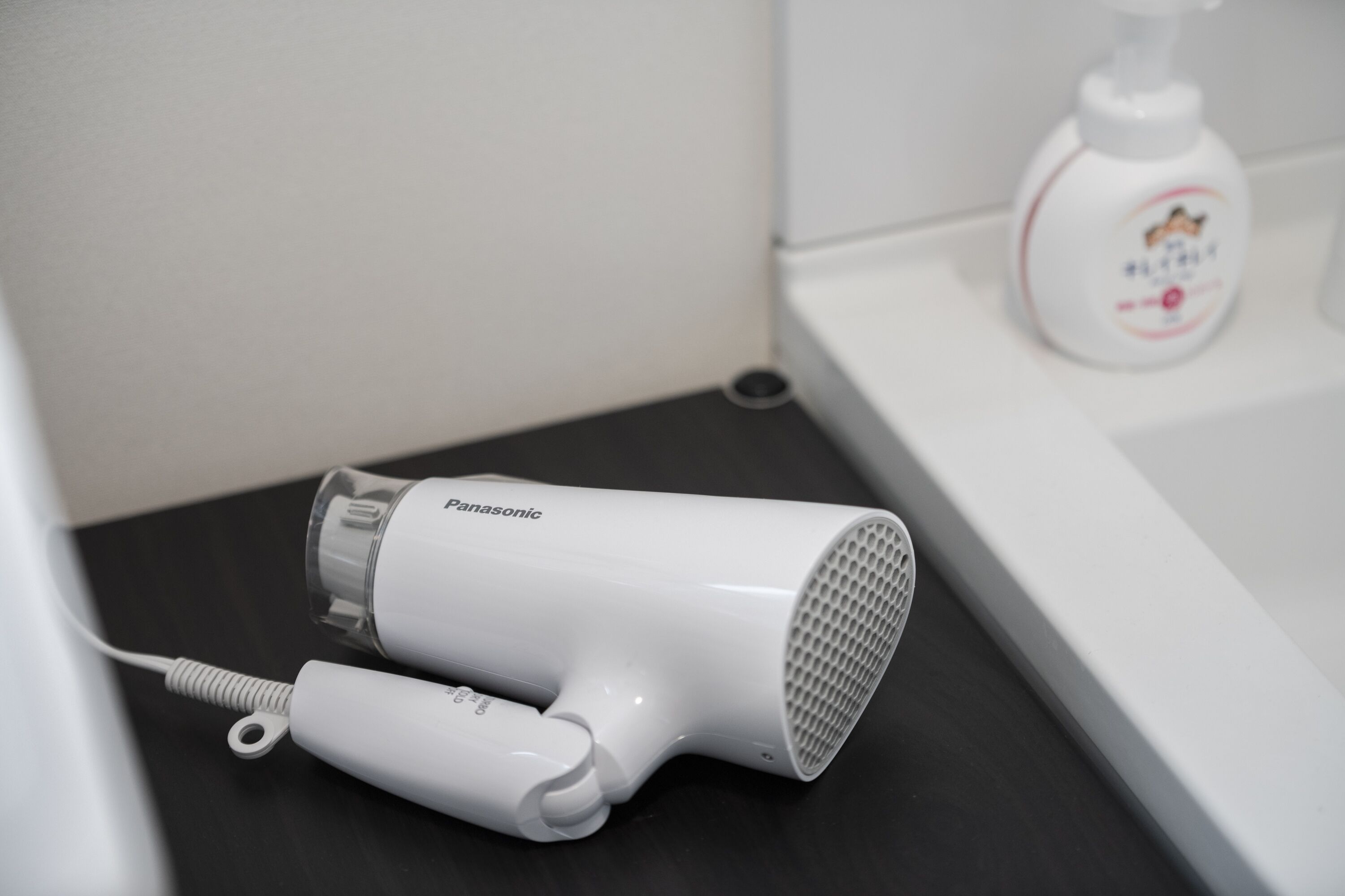 Een Panasonic haardroger op een zwart aanrecht in een badkamer.