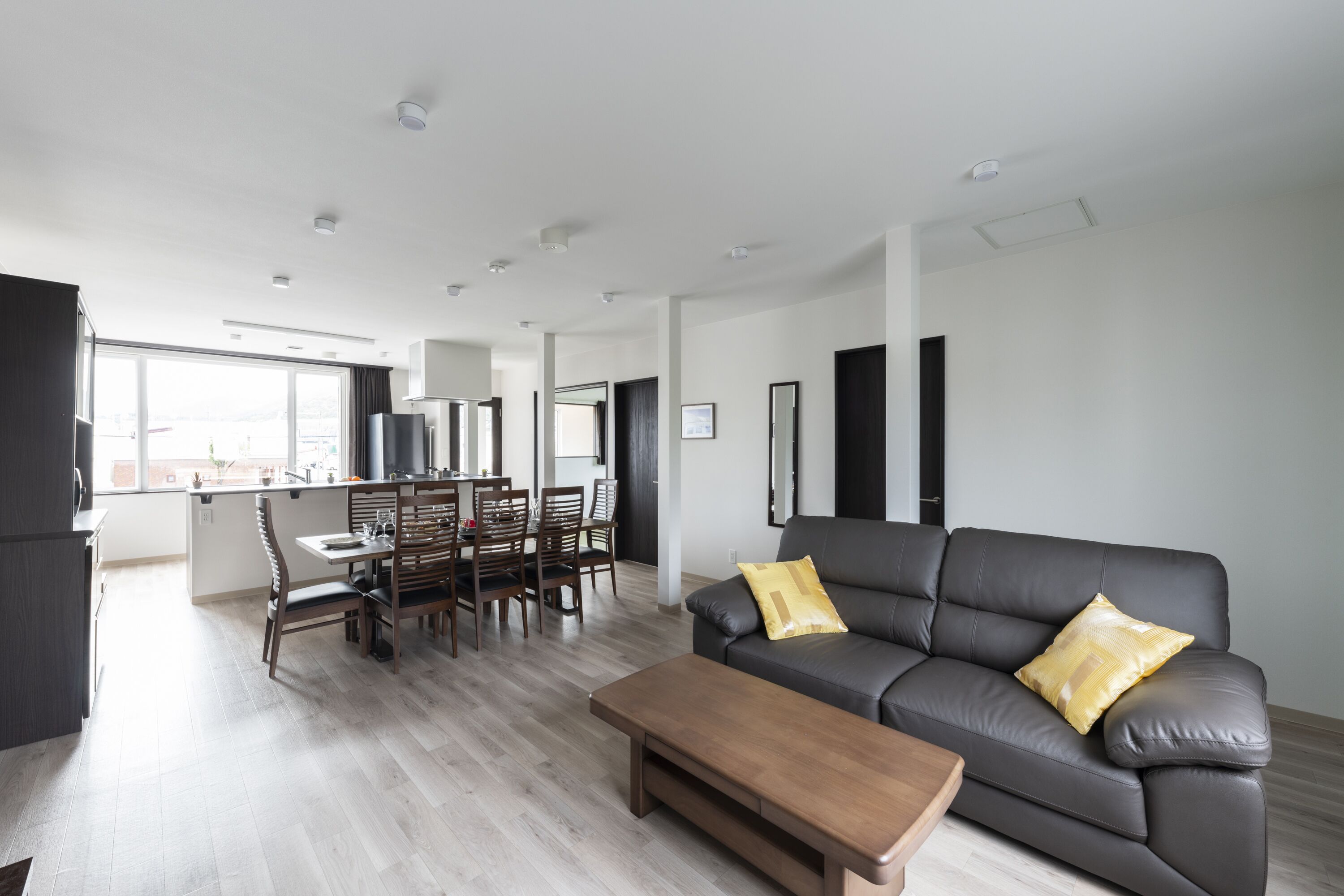 Un salon moderne avec un canapé gris, une table basse en bois et un coin repas comprenant des chaises et une table.