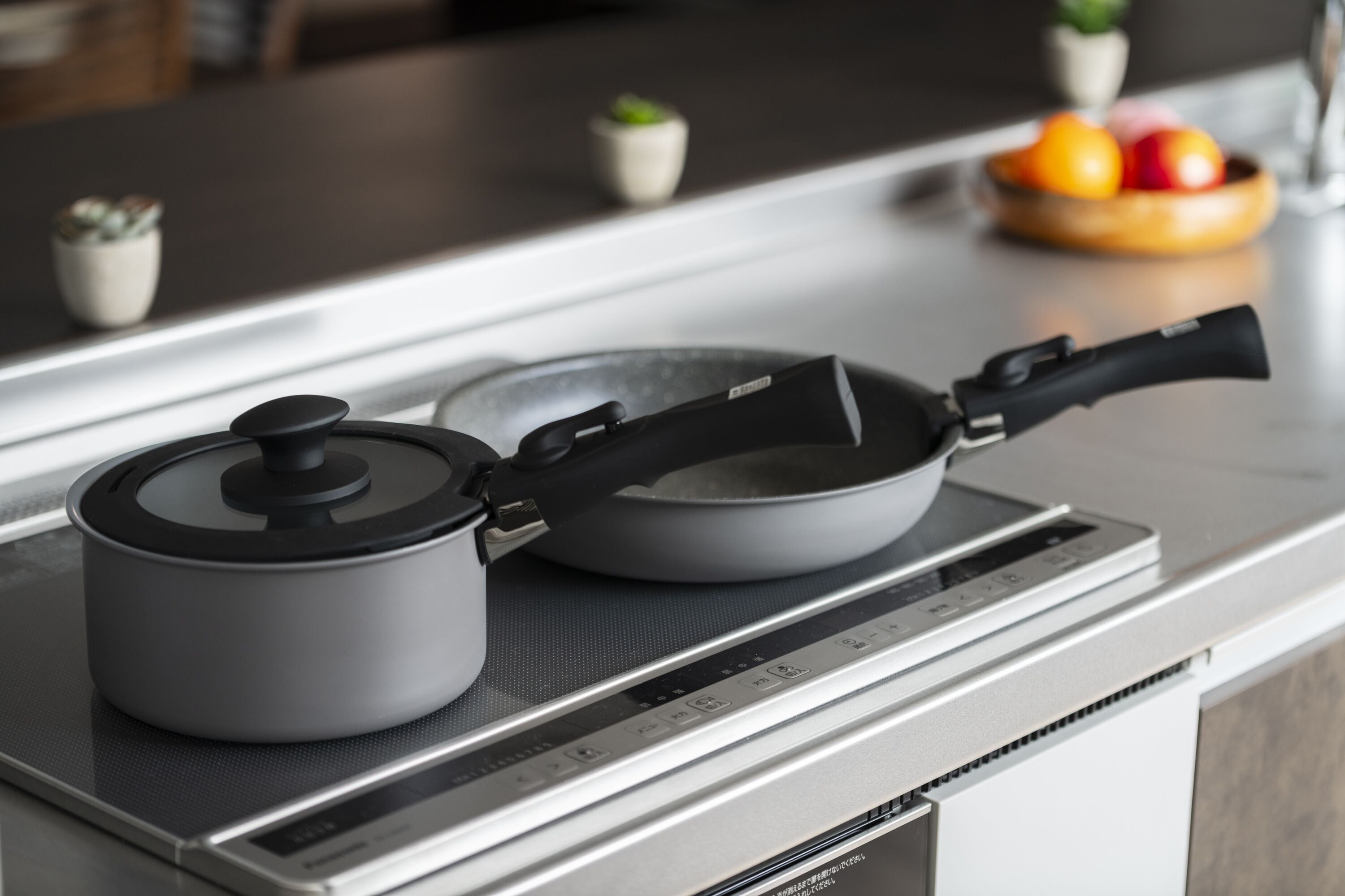 A kitchen with a modern induction cooktop, a kettle, and a frying pan on it.