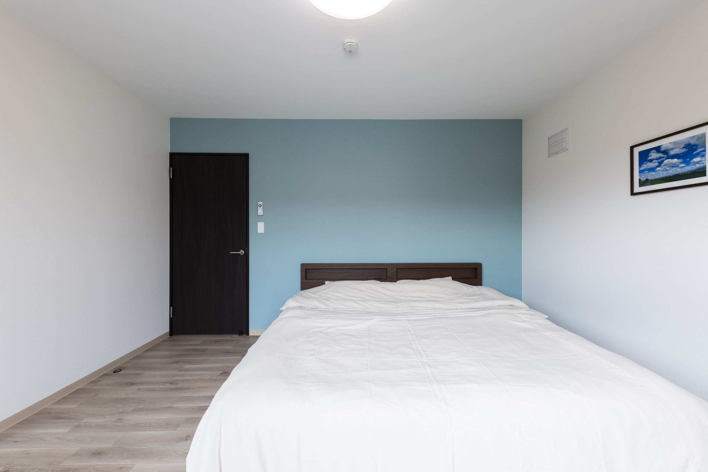 Une chambre à coucher avec un lit, une porte et un tableau accroché au mur.