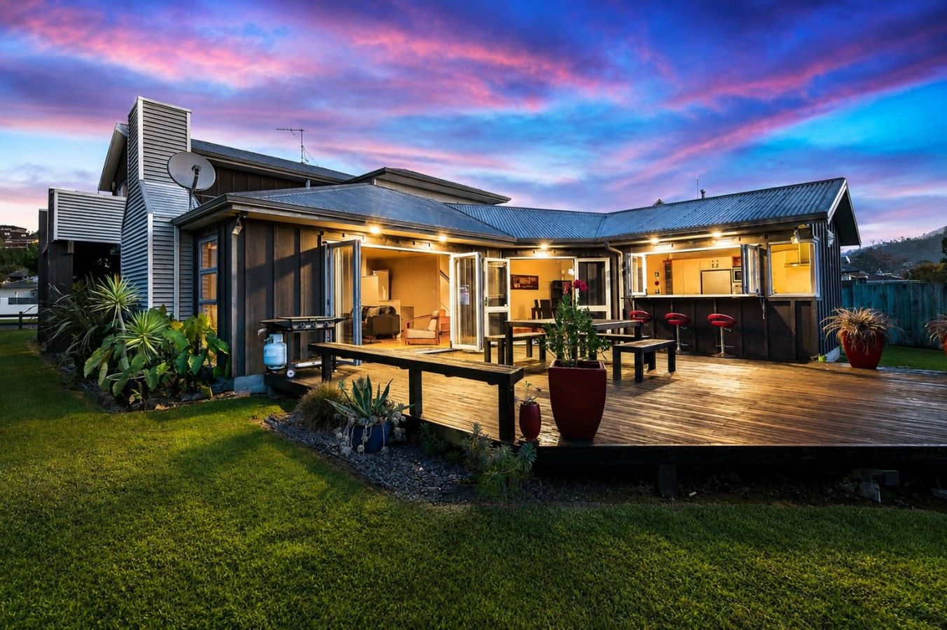 A modern house with a covered patio, outdoor seating, and a well-maintained garden.