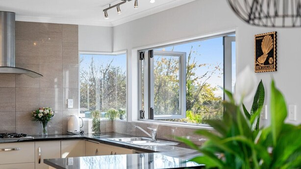 Una cocina moderna con un amplio ventanal, una campana extractora de acero inoxidable y un aplique de pared.
