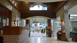 A hotel lobby with a reception desk, a large arched doorway, and a chandelier. -  شقق لمسات الخير للوحدات السكنية - شقق مخدومة (Jeddah)