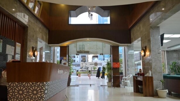 A hotel lobby with a reception desk, a large arched doorway, and a chandelier. - شقق لمسات الخير للوحدات السكنية - شقق مخدومة (Jeddah)