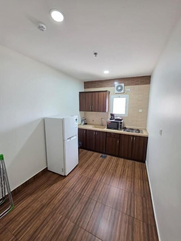 Cocina compacta con refrigerador, armarios y microondas.
