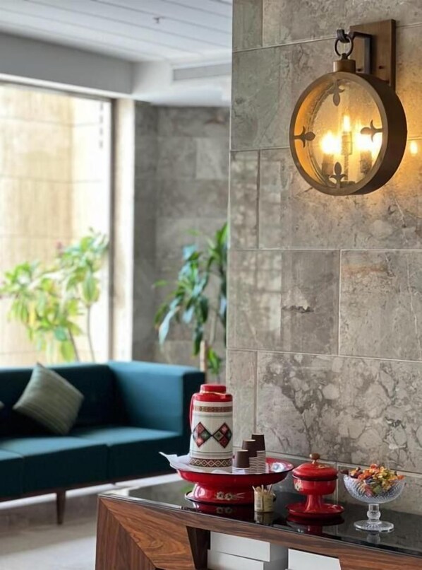 A modern living room with a sofa, a coffee table with decorative items, and a wall-mounted light fixture. -  شقق لمسات الخير للوحدات السكنية - شقق مخدومة (Jeddah)