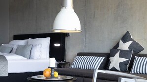 A modern bedroom with a bed, a sofa, a round table with fruit, and a pendant light. - Loft - Neu ab 15.01.2024 - Cityloft- Modernes Appartement für 2 Personen in Zentraler Lage (Sylt)