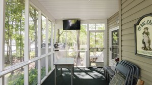 Eine überdachte Veranda mit Tisch, Stühlen und Fernseher.