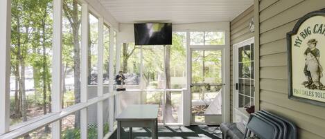 A covered porch with a table, chairs, and a television.