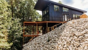 Een modern herenhuis met een balkon, omringd door bomen en een hoop stenen.