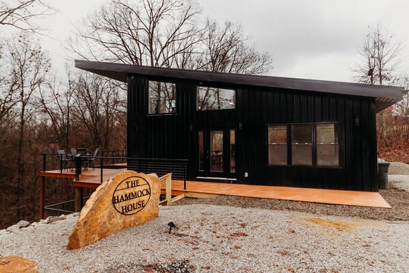 Un bâtiment moderne de couleur noire, doté d’une terrasse et d’une enseigne indiquant : « THE HAMMOCK HOUSE ».