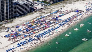 Une vue aérienne d’une plage où l’on voit de nombreux parasols et des gens.