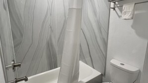 A bathroom with a bathtub, shower, and toilet. - Rodeway Inn Mineola (Mineola)