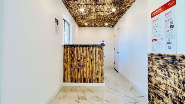 A reception area with a wooden reception desk, a bulletin board, and a marble-tiled floor. - Rodeway Inn Mineola (Mineola)