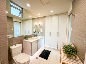 Features a standalone sink, toilet, and large mirror in a minimalist design.