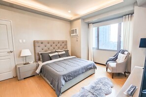 Relax in a spacious room with a large bed, bedside table, and comfortable chair.