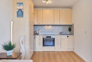 A compact kitchen with wooden cabinets, a built-in oven, and a granite countertop.