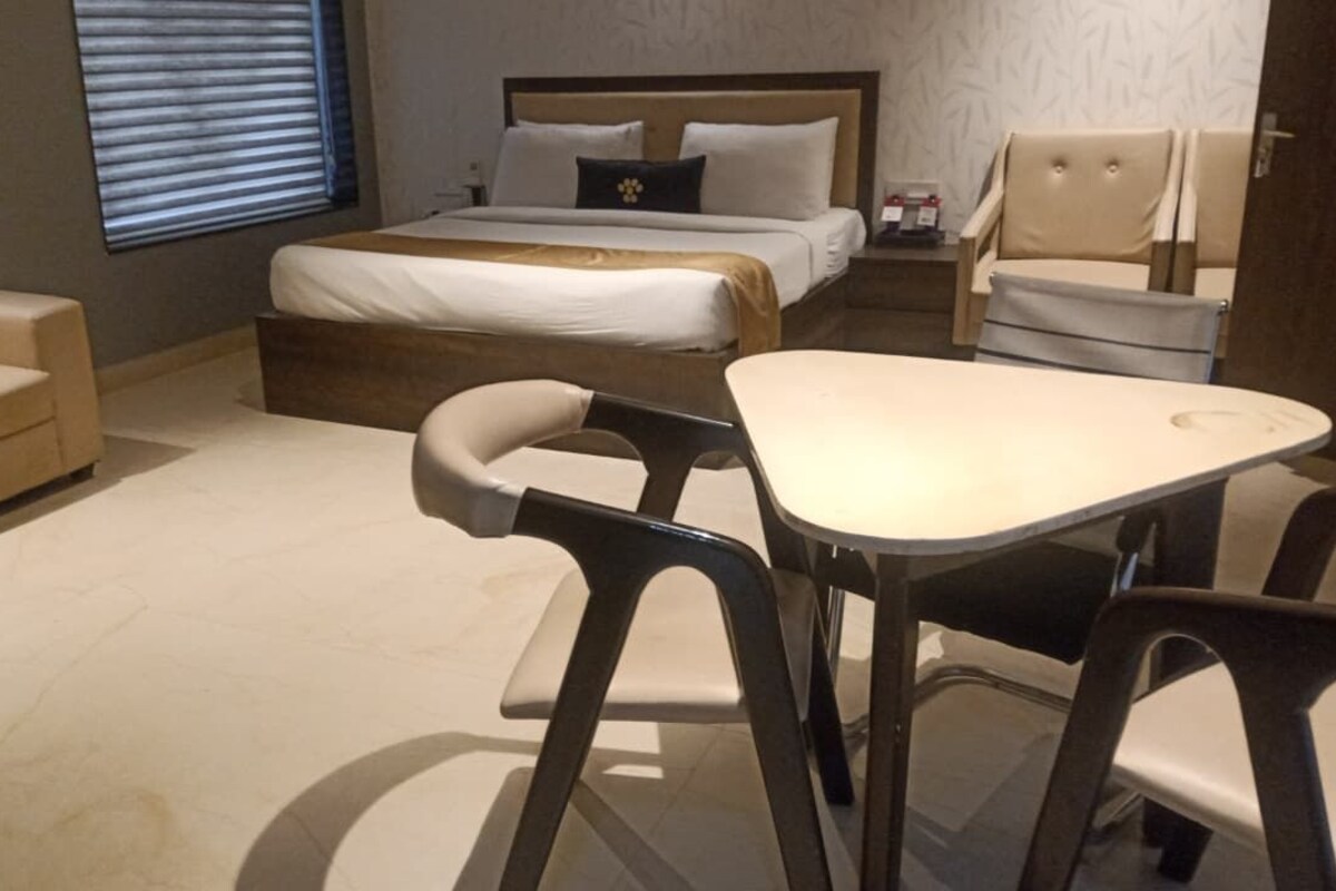 A hotel room with a bed, a sofa, a dining table, and two chairs.