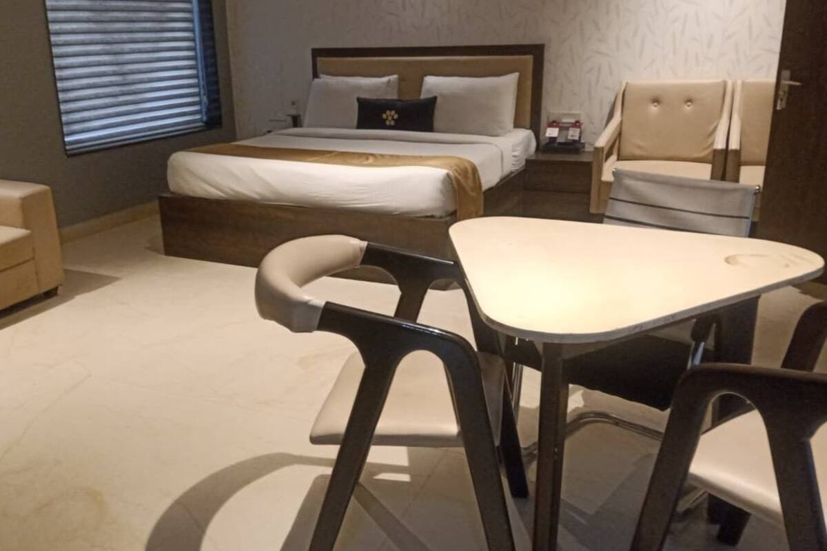 Una habitación de hotel con cama, sofá, mesa de comedor y dos sillas.