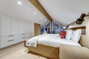 A bedroom with a sloped ceiling, built-in wardrobe, and a bedside table with a lamp. - Nighthawk 3343 - Private Hot Tub, Mountain Views, Above Whistler Golf Course (Whistler)