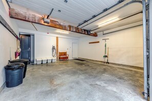 A spacious garage with a concrete floor, a wooden bench, and a door leading to another room. - Located overlooking the Whistler Golf Course, mountain charm, unbeatable views (Whistler)