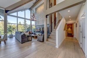 A spacious living room with a large window, a fireplace, and a staircase leading to an upper level.