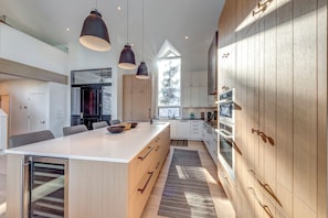 A modern kitchen with a central island, wooden cabinets, and pendant lighting.
