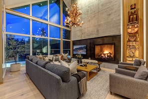 A modern living room with a large sofa, a fireplace, and a television.