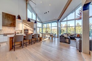 A spacious kitchen with a central island, bar seating, and a dining area with a view of the outdoors. - Nighthawk 3343 - Private Hot Tub, Mountain Views, Above Whistler Golf Course (Whistler)