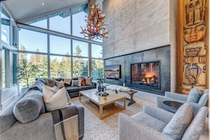 A modern living room with a large fireplace, a sofa set, and a totem pole.
