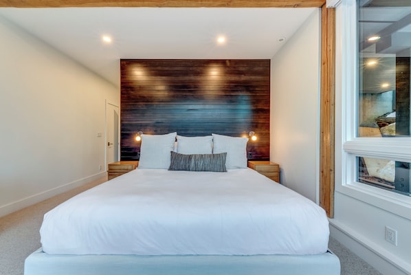 A bedroom with a large bed, wooden headboard, bedside tables, and a window.