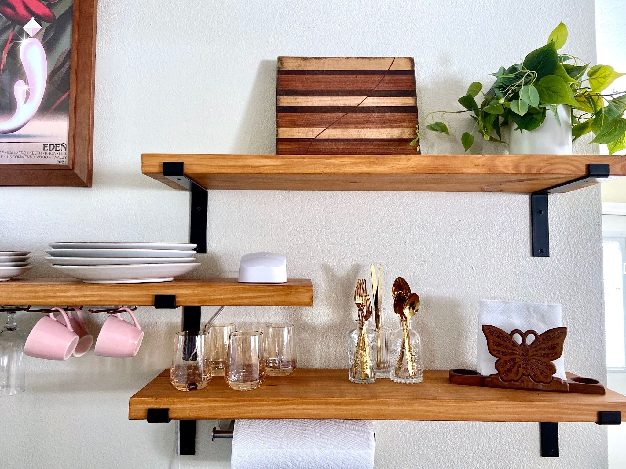 Une étagère en bois où sont disposées des assiettes, des verres et des objets décoratifs.