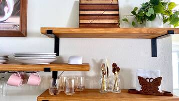 Une étagère en bois où sont disposées des assiettes, des verres et des objets décoratifs.