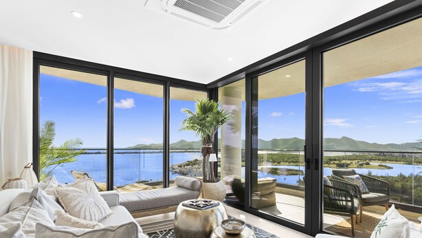 Ein modernes Wohnzimmer mit einer großen Glasdoor, die auf einen Balkon mit herrlichem Seeblick und Bergblick führt.