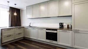 A modern kitchen with white cabinetry, a built-in oven, and a window with curtains.