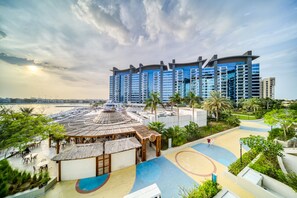 A resort with a pool area, a beach, and a large hotel building. - Vibrant Palm Lifestyle and Mediterranean Charm (Dubai)
