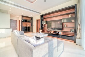 Un salon moderne doté d’un grand téléviseur à écran plat, d’un canapé d’angle gris et d’une table basse au design minimaliste.