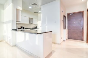Une cuisine moderne avec des meubles blancs, un plan de travail noir et une porte en bois.