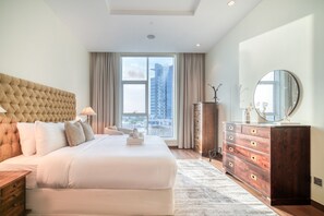 Een moderne hotelkamer met een groot bed, een dressoir, een spiegel en uitzicht op de stad.