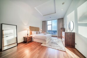 A modern hotel room with a large bed, a wooden floor, a view of the city, and a mirror on the wall. - Vibrant Palm Lifestyle and Mediterranean Charm (Dubai)