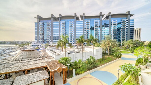 Ein Resort mit einem großen Gebäude, einem Pool und Palmen.